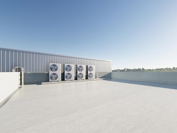 Commercial-Roof-Replacement-Canyon-Lake-CA-California-2 | Woolbright's Roofing & Construction Rooftop scene with a row of outdoor air conditioning units along a metal wall and a body of water in the distance under a clear blue sky.