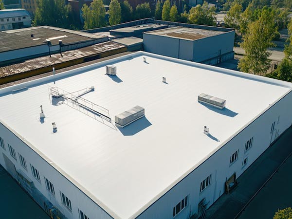 Flat-Roof-Installation-Canyon-Lake-CA-California-2 | Woolbright's Roofing & Construction Aerial view of a white flat-roofed industrial building with multiple HVAC units and vents.